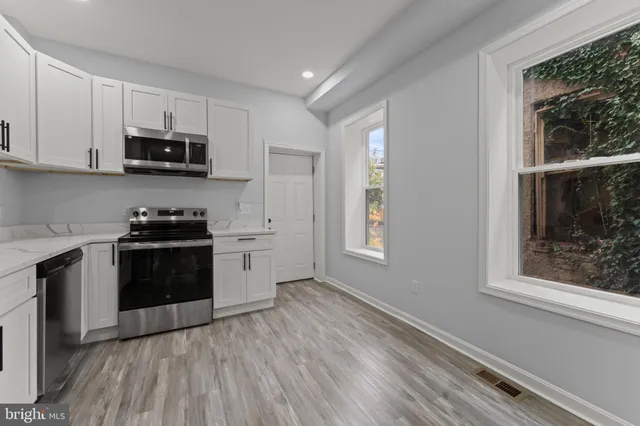 a kitchen with stainless steel appliances a sink a stove a refrigerator cabinets and a window