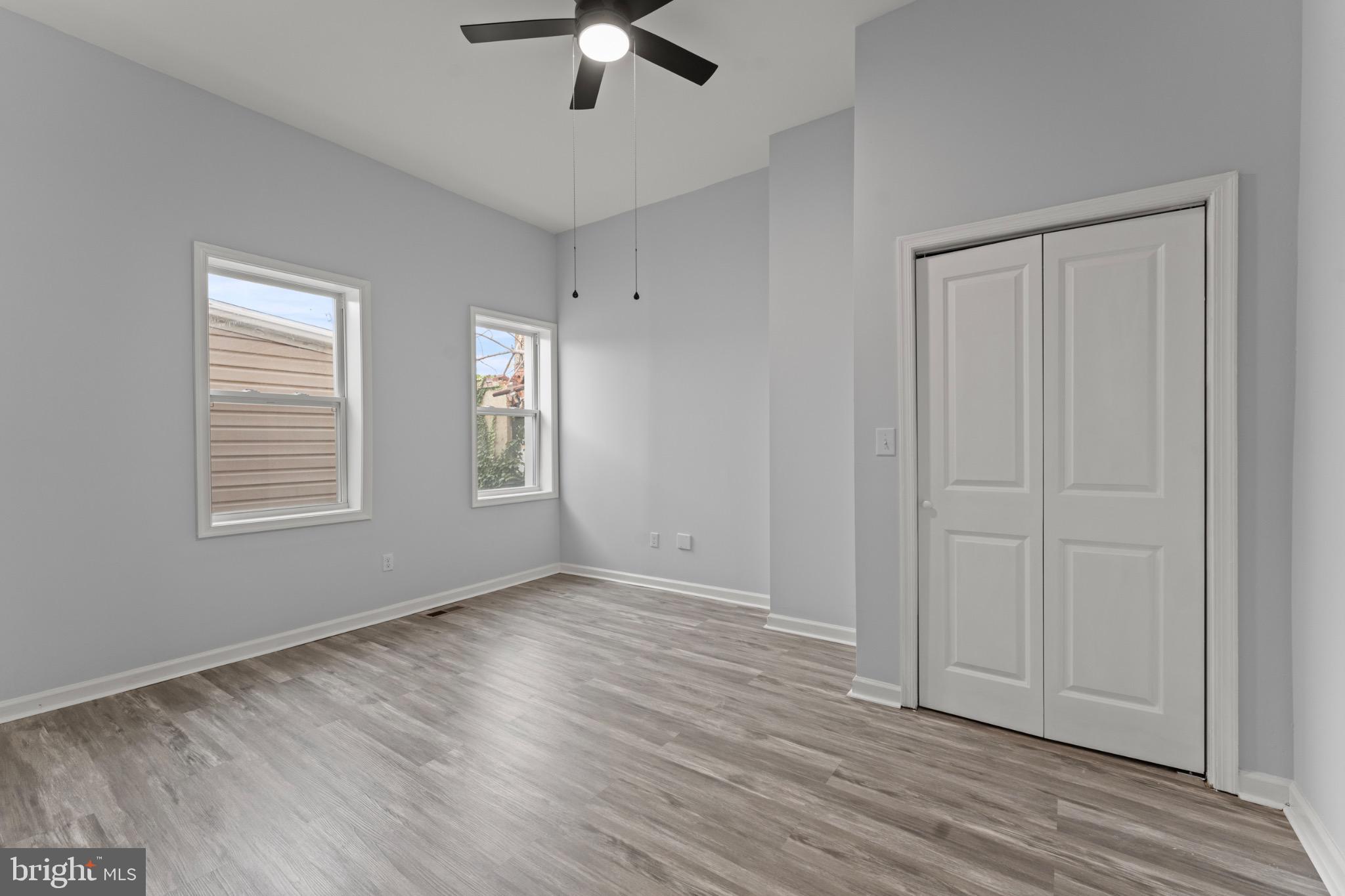 917 Edmondson Avenue Baltimore, MD 21223 - Photo 15 of 27 an empty room with wooden floor chandelier fan and windows