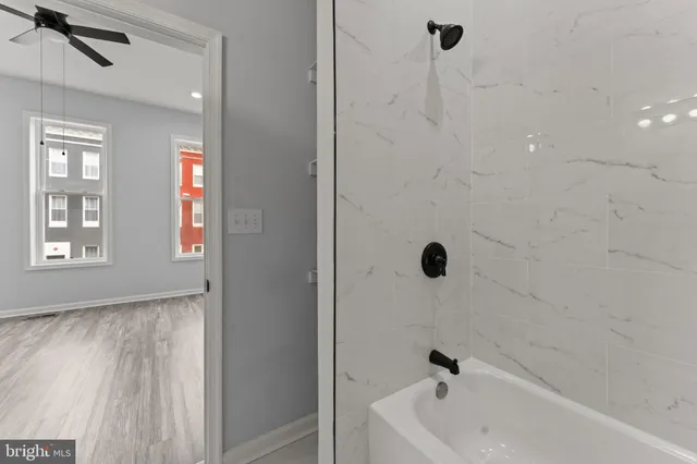 a view of empty room with wooden floor and fan