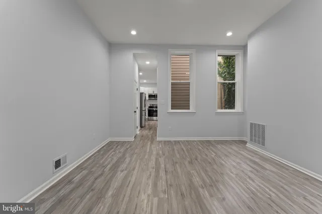 an empty room with wooden floor and windows