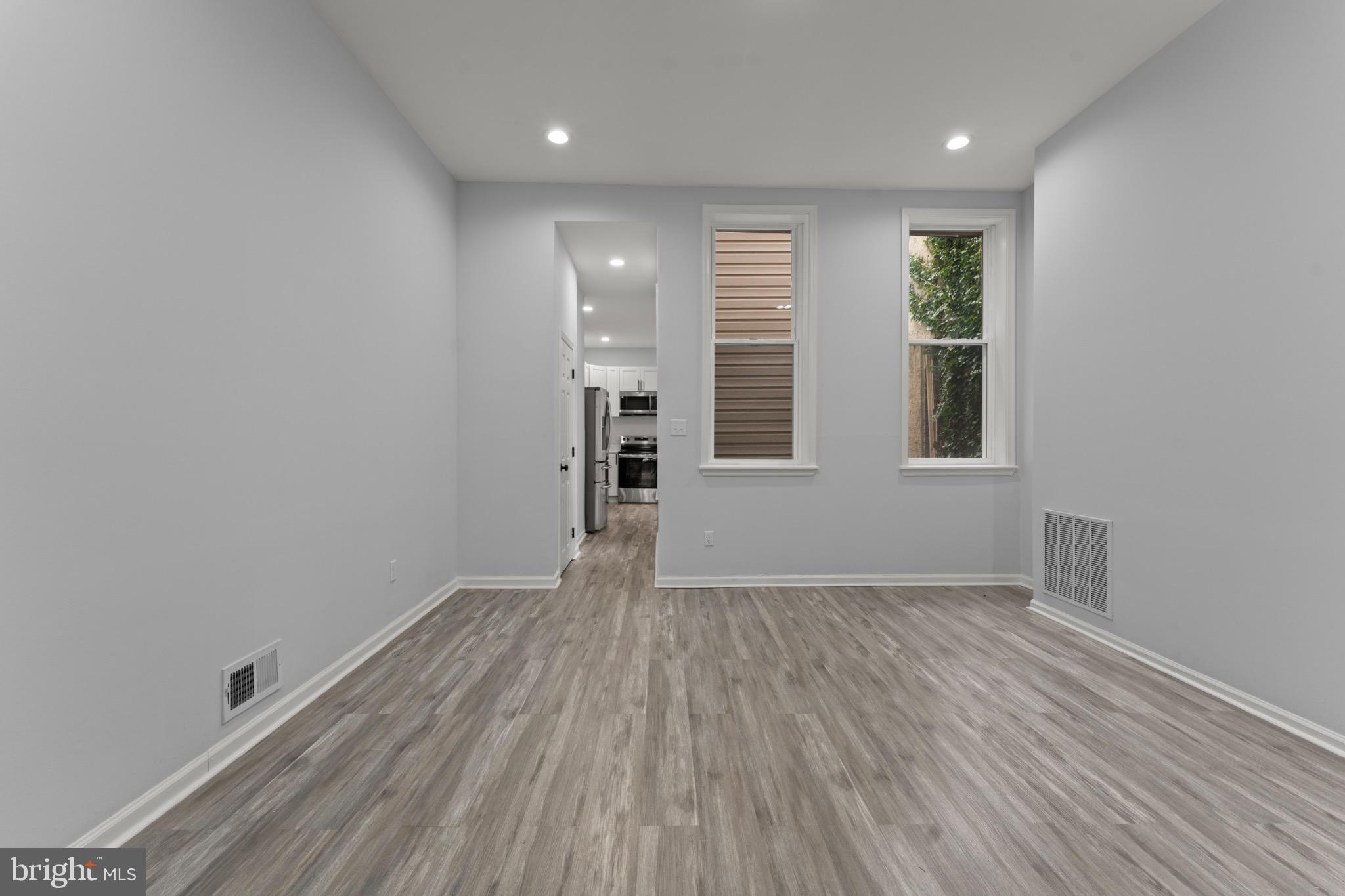 917 Edmondson Avenue Baltimore, MD 21223 - Photo 7 of 27 an empty room with wooden floor and windows