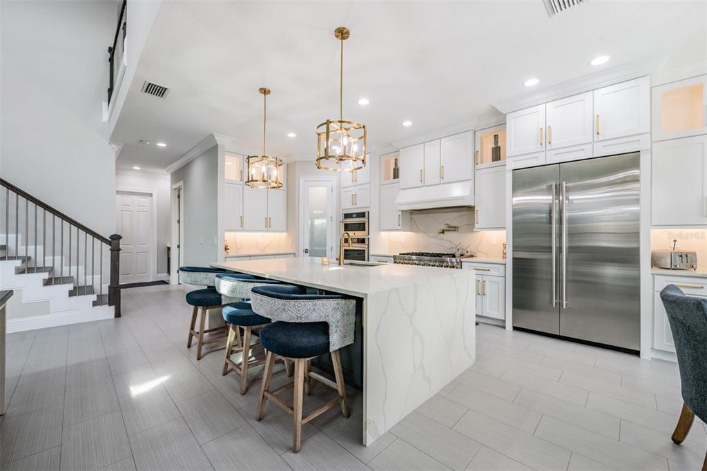 2913 Valencia Ridge Street Valrico, FL 33596 - Photo 13 of 31 a kitchen with stainless steel appliances kitchen island granite countertop a table chairs in it and wooden floors