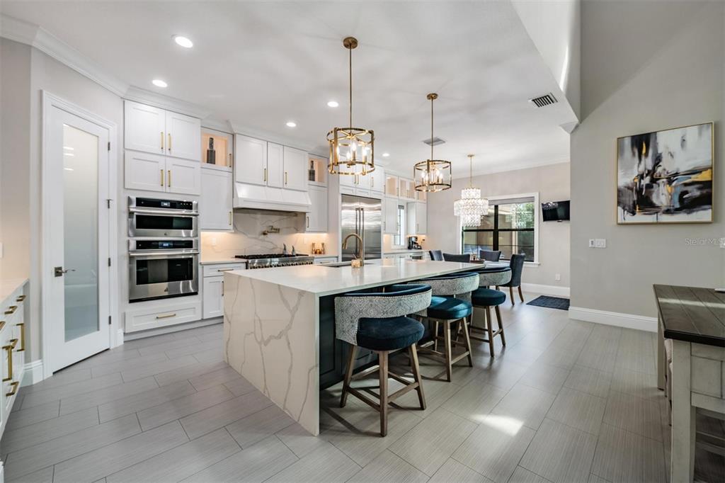 2913 Valencia Ridge Street Valrico, FL 33596 - Photo 2 of 31 a kitchen with kitchen island a dining table chairs and white cabinets