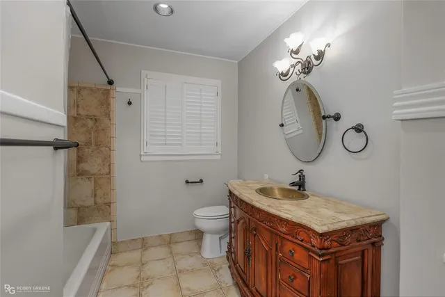 a bathroom with a granite countertop sink a toilet and shower