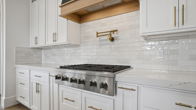 1682 North 1950 W Street, Unit 9 Provo, UT 84604 - Photo 24 of 84 Gourmet kitchen featuring a stainless steel range, a brass pot filler, white shaker-style cabinetry with brass hardware, a light wood-finish range hood, and a white subway tile backsplash