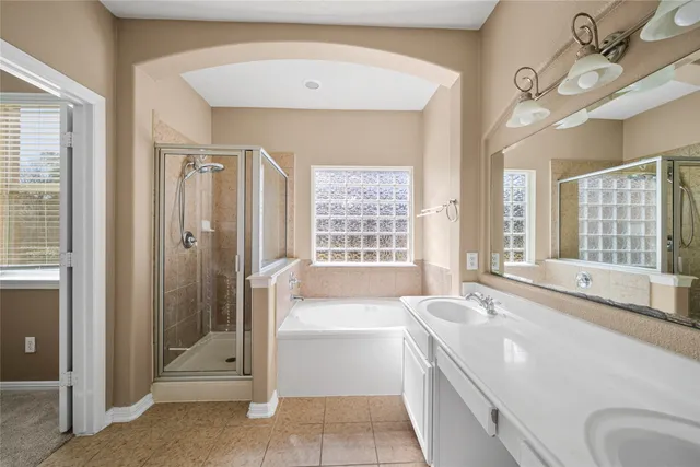 a spacious bathroom with a granite countertop sink a mirror and a bathtub