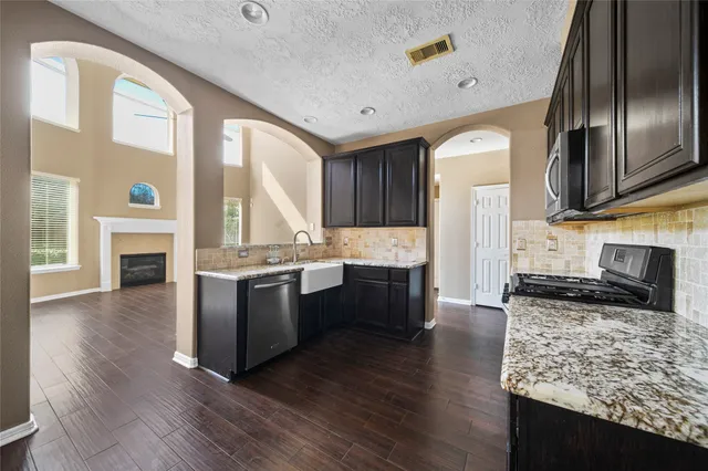 a large kitchen with stainless steel appliances granite countertop a stove a sink and a refrigerator