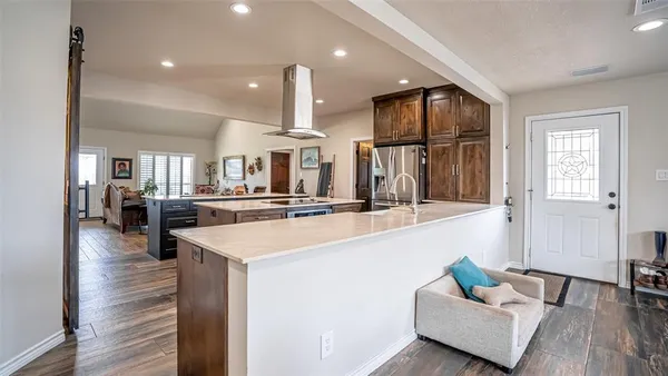 a hall with kitchen island stainless steel appliances wooden floor and living room view