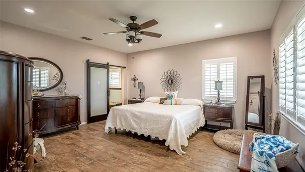 a bedroom with a bed a mirror on dresser and a chandelier
