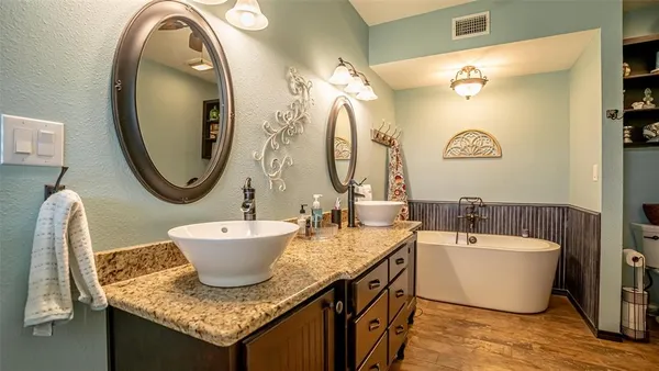 a bathroom with a granite countertop double vanity sink and a mirror