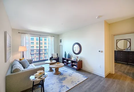 a living room with furniture a rug a window and a lamp