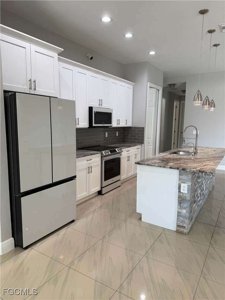 3013 4th Street West Lehigh Acres, FL 33971 - Photo 10 of 47 a kitchen with stainless steel appliances a refrigerator sink and microwave