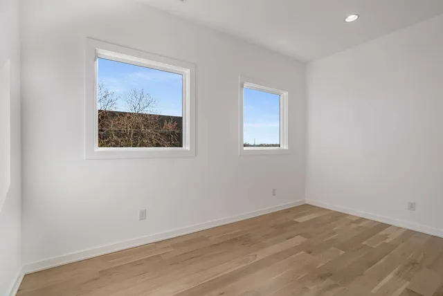 a view of an empty room with a window and a kitchen view