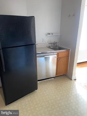 a view of a refrigerator in kitchen and an empty room