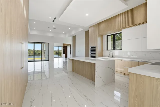 a large white kitchen with granite countertop a sink and dishwasher a stove with wooden floors