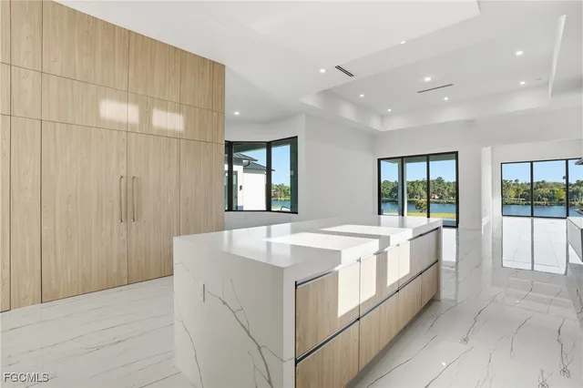 a large white kitchen with a sink and large window