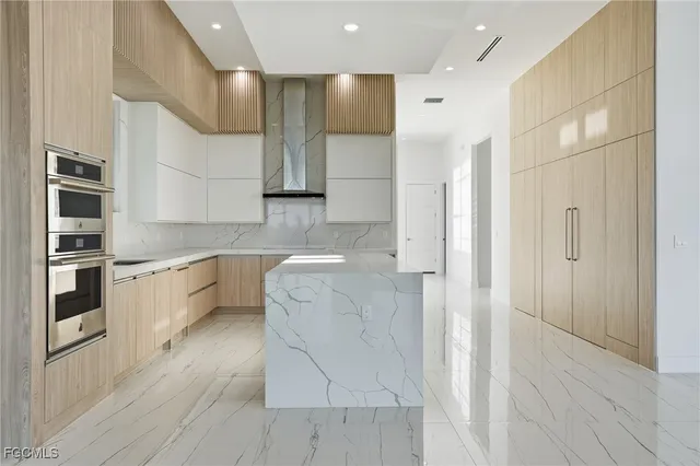 a large white kitchen with kitchen island a sink stainless steel appliances and cabinets