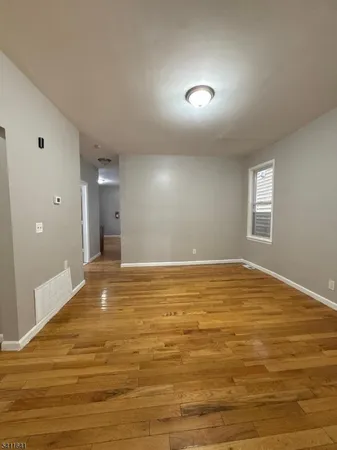 a view of empty room with window and wooden floor