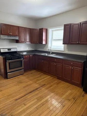 a kitchen with stainless steel appliances granite countertop wooden cabinets a stove top oven a sink and dishwasher