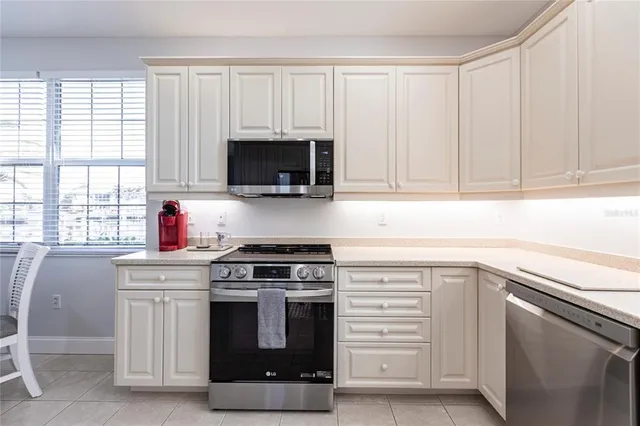 a kitchen with white cabinets stainless steel appliances and window