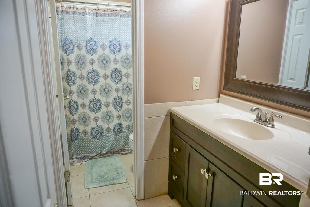 254 Thrift Street Mobile, AL 36609 - Photo 12 of 16 Bathroom featuring vanity, tile patterned floors, a shower with shower curtain, and tile walls