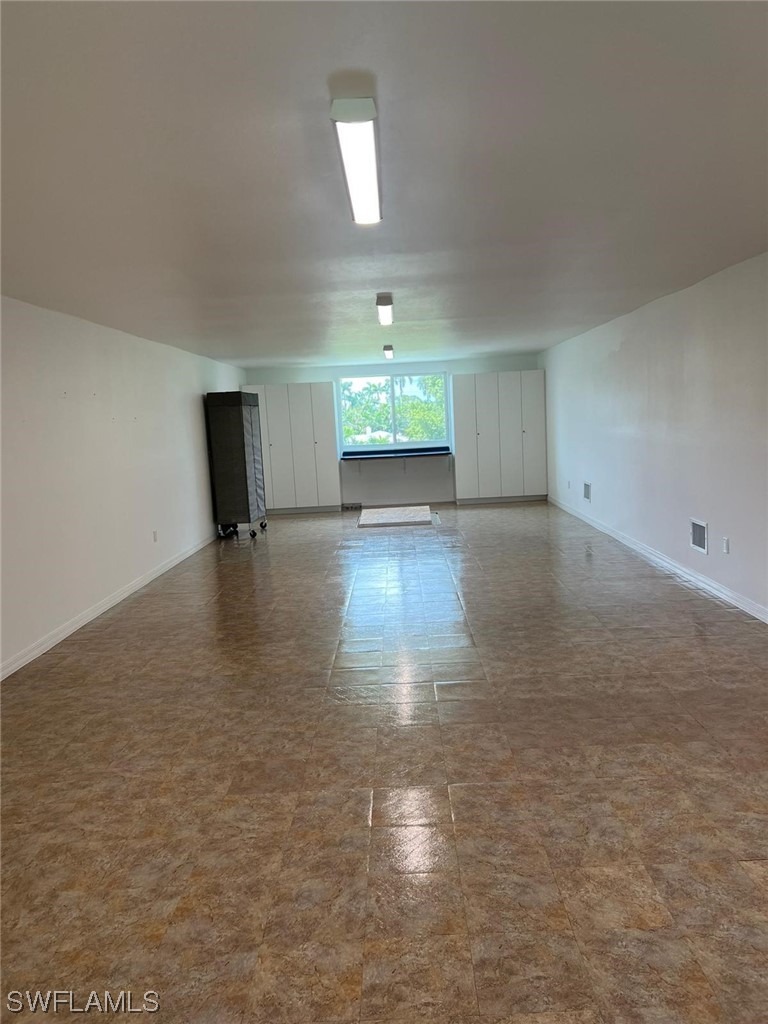 1337 Bradford Road Fort Myers, FL 33901 - Photo 36 of 46 an empty room with wooden floor chandelier and windows