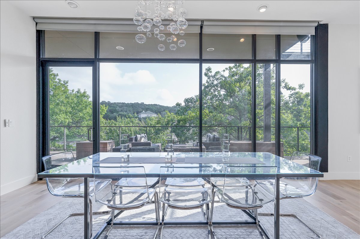 1101 Ivean Pearson Road, Unit A102 Lago Vista, TX 78645 - Photo 11 of 31 Dining space featuring light wood-style floors, a chandelier, floor to ceiling windows, view of scattered trees, and healthy amount of natural light