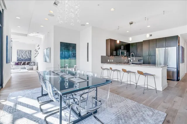 a kitchen with stainless steel appliances kitchen island granite countertop a stove a sink a oven a dining table and chairs