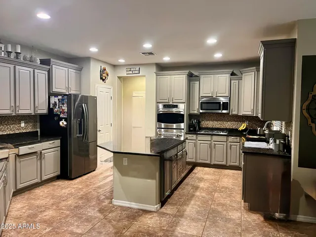 a kitchen with stainless steel appliances granite countertop a refrigerator stove top oven and sink