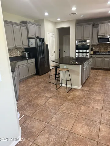 a kitchen with stainless steel appliances granite countertop a stove a sink a microwave a refrigerator and cabinets