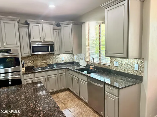 a kitchen with stainless steel appliances granite countertop a sink stove and microwave