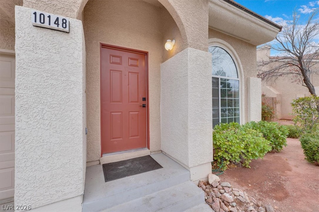 10148 Tree Bark Street Las Vegas, NV 89183 - Photo 2 of 37 An inviting entry framed by an arched portico, complemented by manicured landscaping and an arched window.