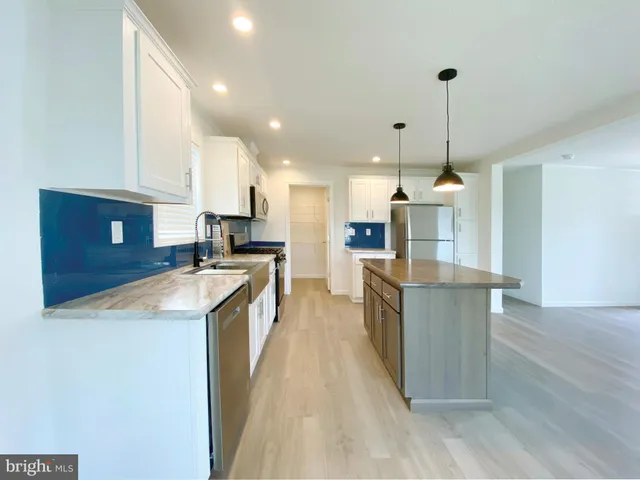 a kitchen with stainless steel appliances granite countertop a sink a stove and a refrigerator