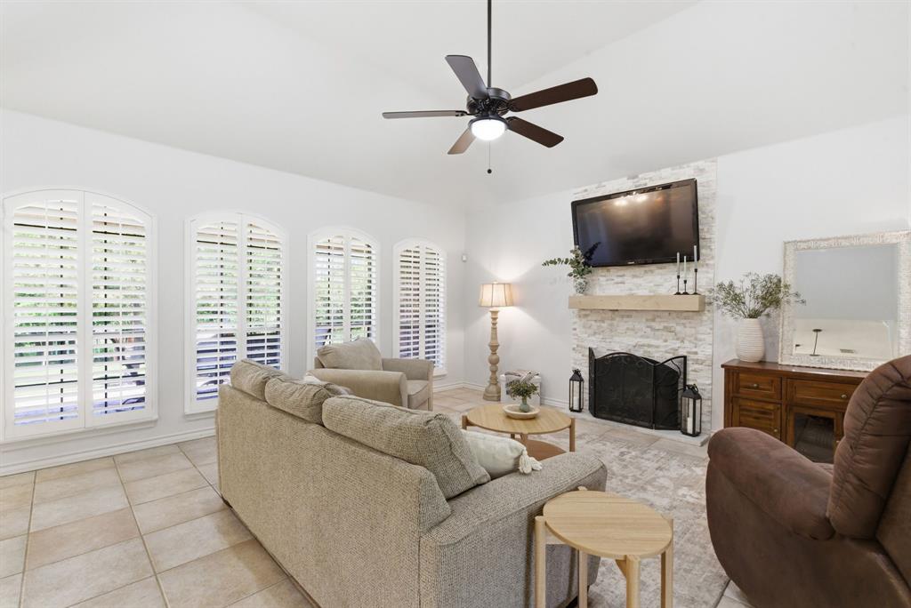 405 Zion Hill Road Weatherford, TX 76088 - Photo 13 of 38 Living area featuring a stone fireplace, ceiling fan, light tile patterned flooring, and vaulted ceiling