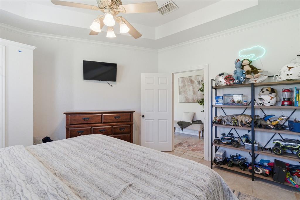 405 Zion Hill Road Weatherford, TX 76088 - Photo 17 of 38 Bedroom featuring a raised ceiling, light tile patterned floors, crown molding, and a ceiling fan