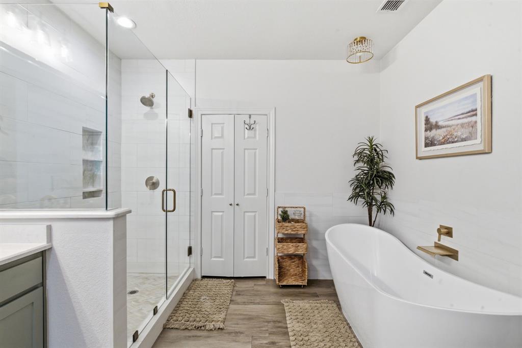 405 Zion Hill Road Weatherford, TX 76088 - Photo 22 of 38 Full bath with a freestanding bath, a stall shower, light wood-type flooring, vanity, and tile walls