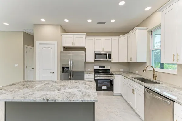 a kitchen with stainless steel appliances granite countertop a sink refrigerator and cabinets
