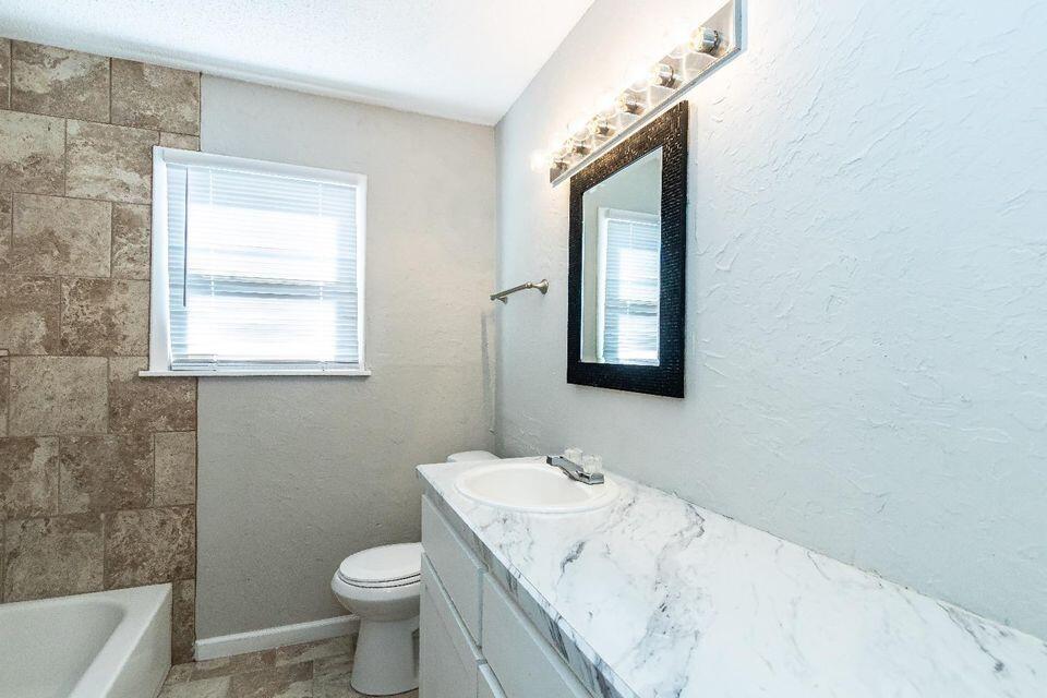 4212 42nd Street Lubbock, TX 79413 - Photo 16 of 18 a bathroom with a sink a toilet and mirror