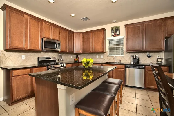 a kitchen with granite countertop a stove sink microwave and cabinets