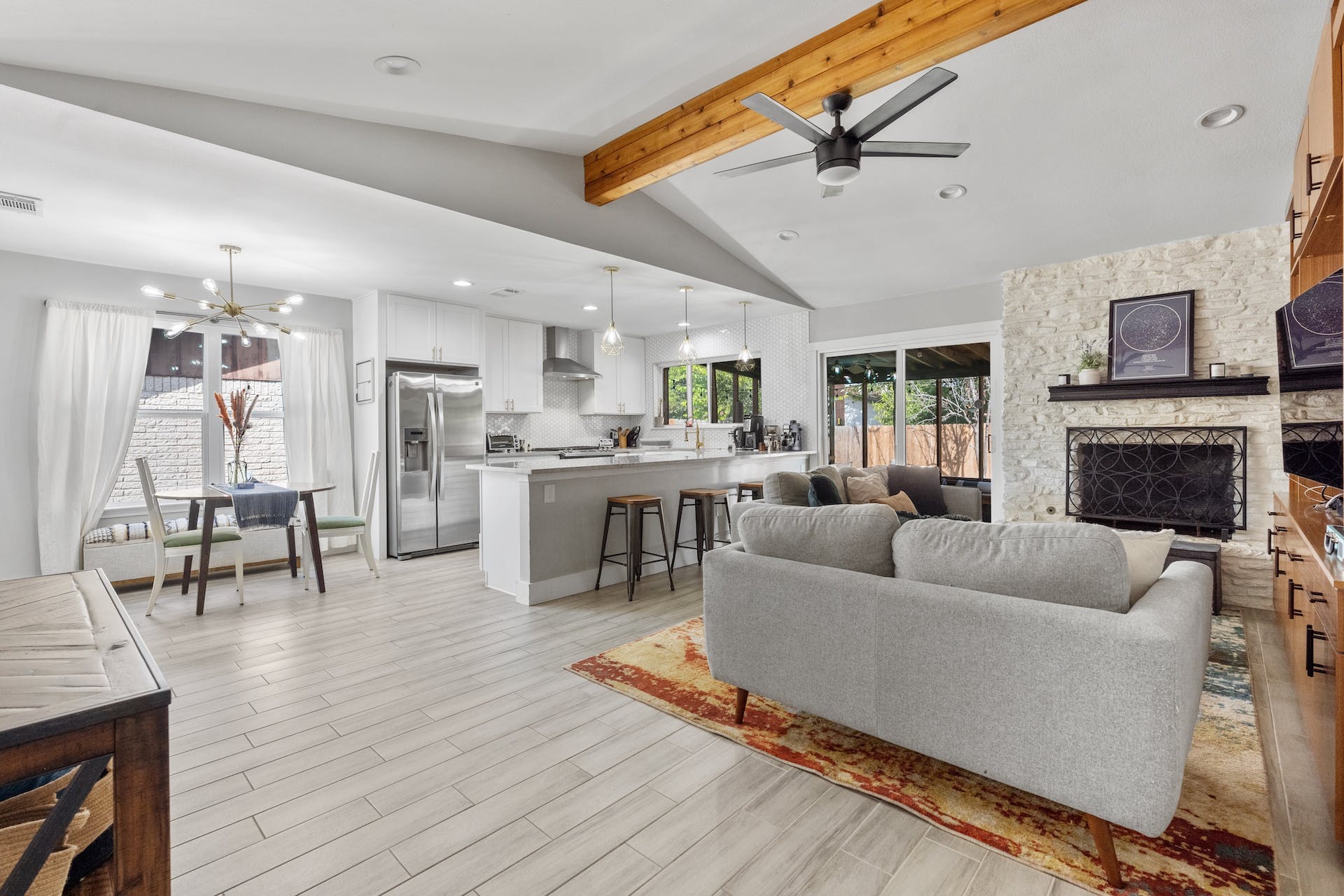 1400 Chippeway Lane Austin, TX 78745 - Photo 3 of 24 Living area with ceiling fan, a fireplace, beamed ceiling, light wood-style flooring, and hanging lights