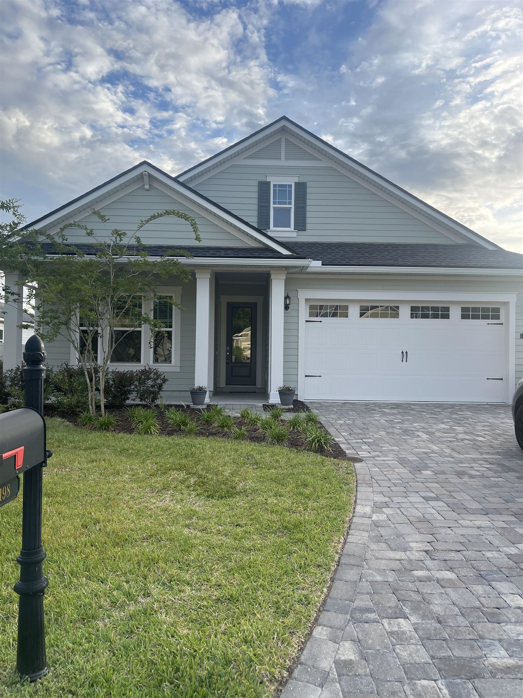 a view of a white house with a small yard and a large tree