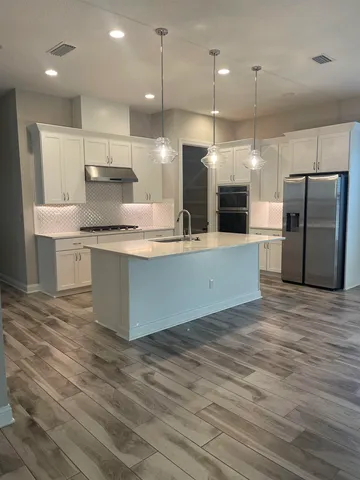 a large kitchen with stainless steel appliances a large counter top a stove a refrigerator and a sink