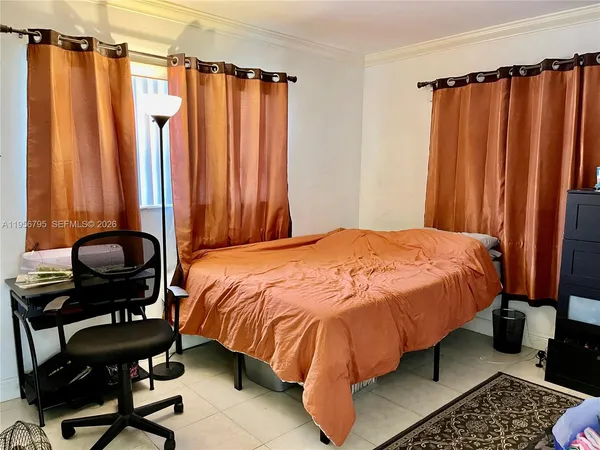 a bedroom with a bed and a dresser next to a window