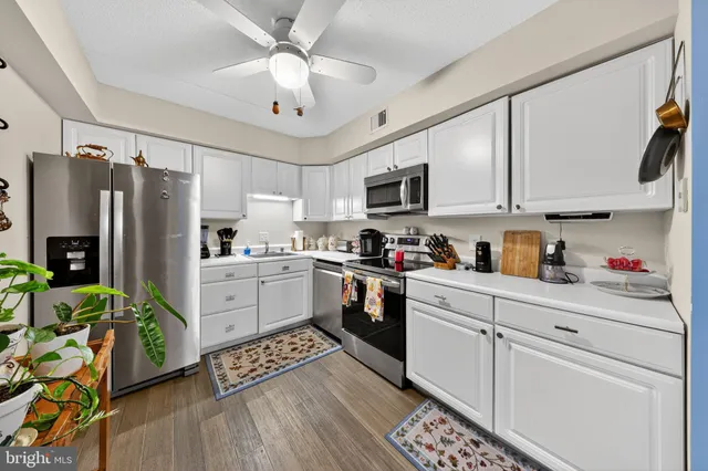 a kitchen with stainless steel appliances sink cabinets and wooden floor