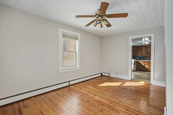 a view of an empty room with wooden floor and a window