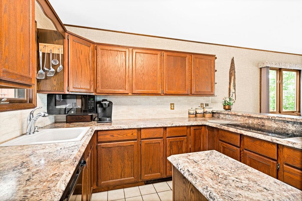 8639 South Strand Lake Road Cotton, MN 55724 - Photo 13 of 50 Kitchen with sink, decorative backsplash, light stone counters, and light tile patterned floors