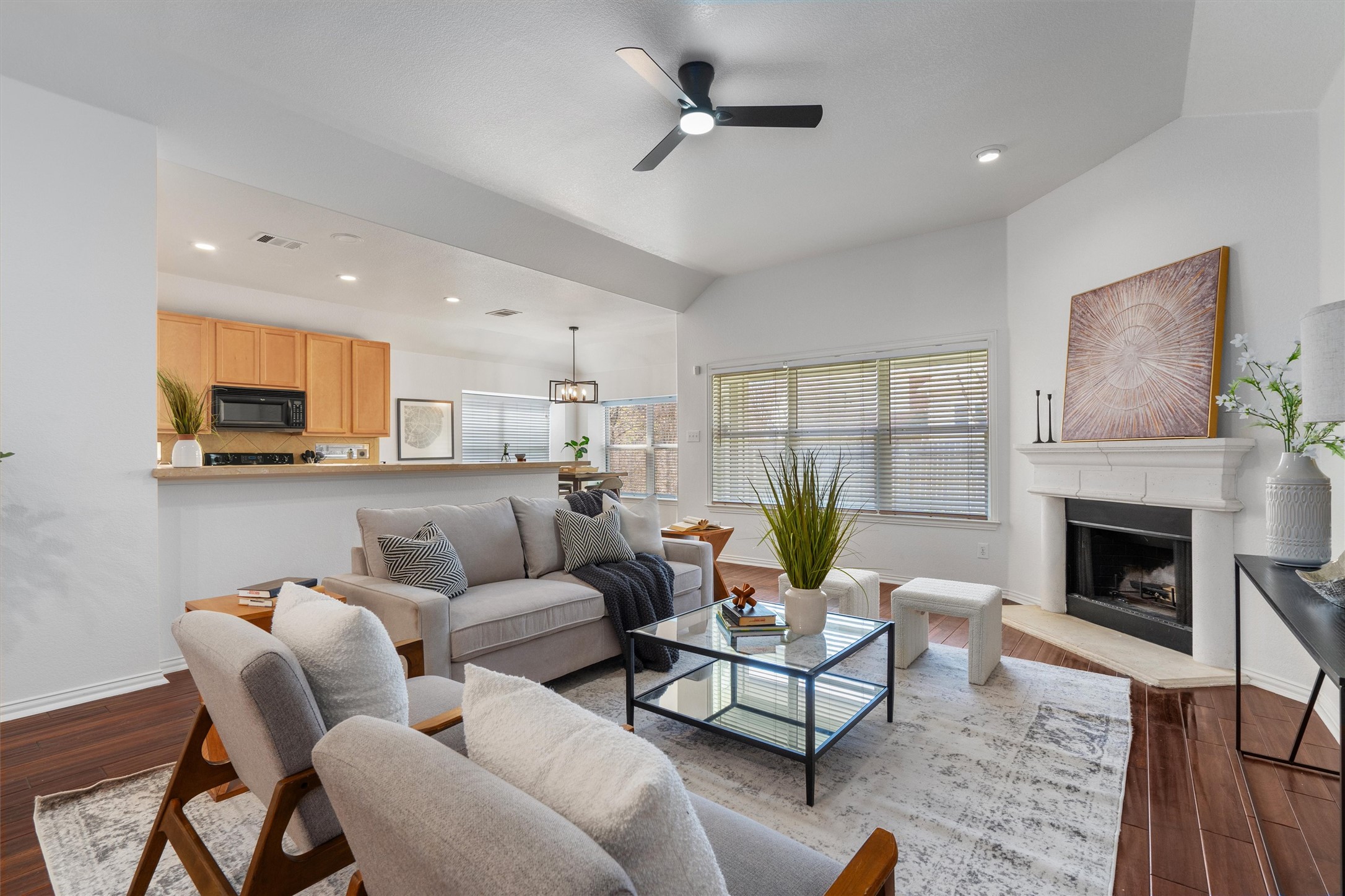 Living area featuring dark wood-style flooring, a ceiling fan, a fireplace with raised hearth, recessed lighting, and vaulted ceiling