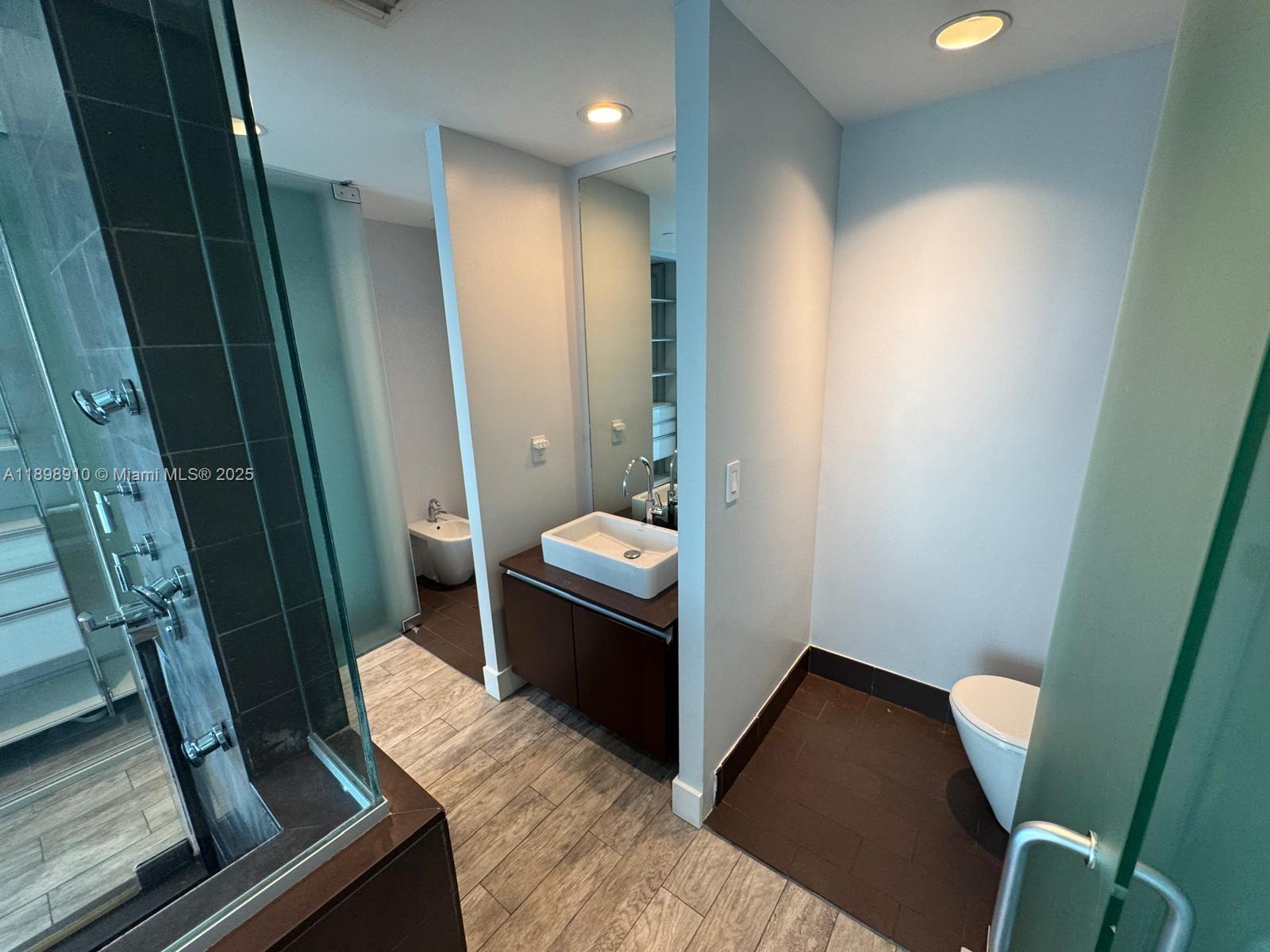 1040 Biscayne Boulevard, Unit 1106 Miami, FL 33132 - Photo 16 of 29 a bathroom with a sink a toilet a mirror and vanity