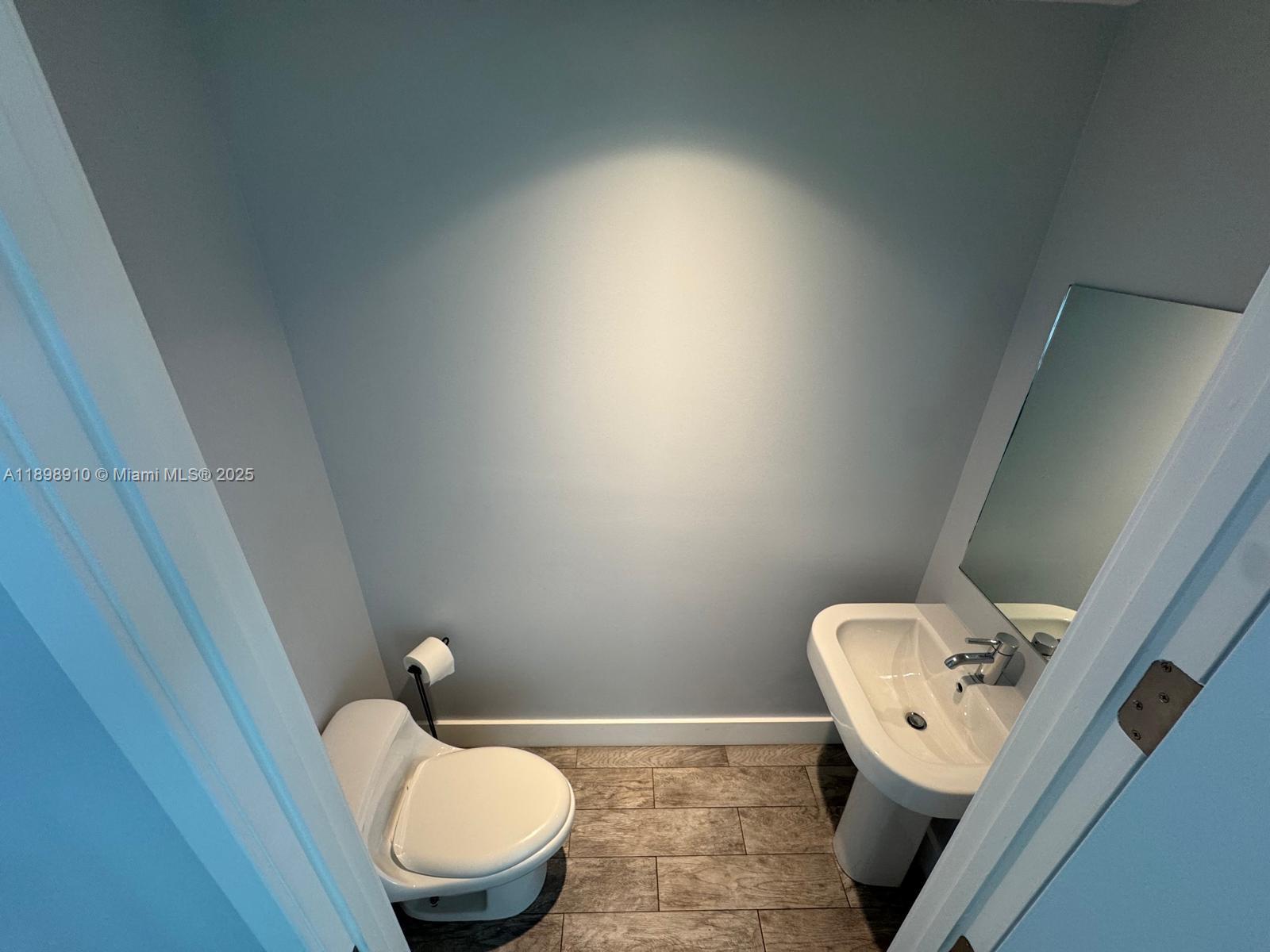 1040 Biscayne Boulevard, Unit 1106 Miami, FL 33132 - Photo 25 of 29 a white toilet sitting next to a wooden cabinet