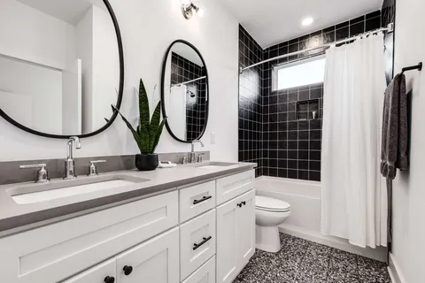 a bathroom with a double vanity sink toilet mirror and shower